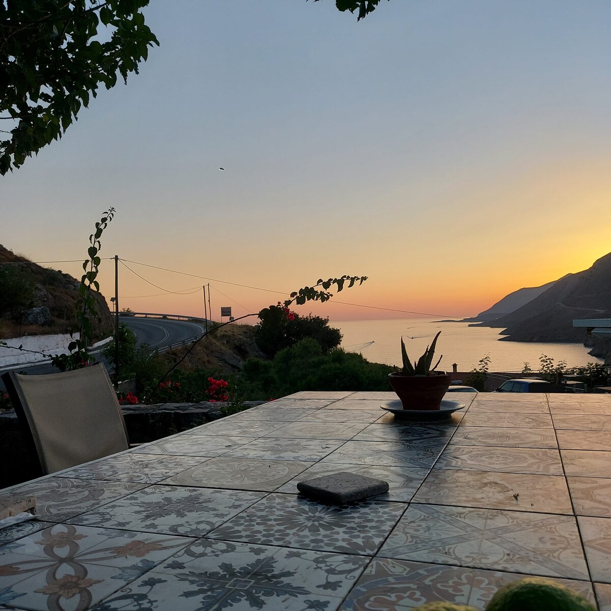 Candlelit table on the terrace at dusk, with the coast behind
